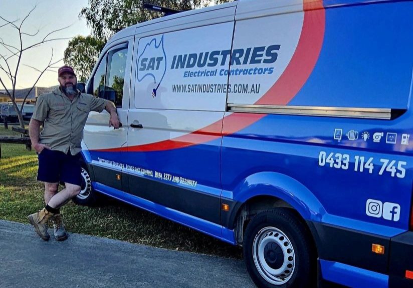 SAT Industries Van with a talented electrical worker standing by the business.